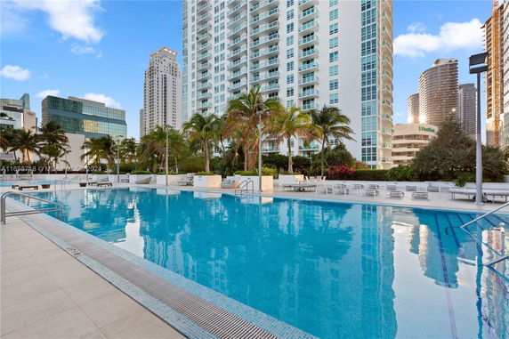 Poolside view with tall modern buildings in the background.