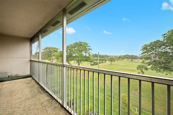 Balcony view overlooking a grassy landscape and trees.