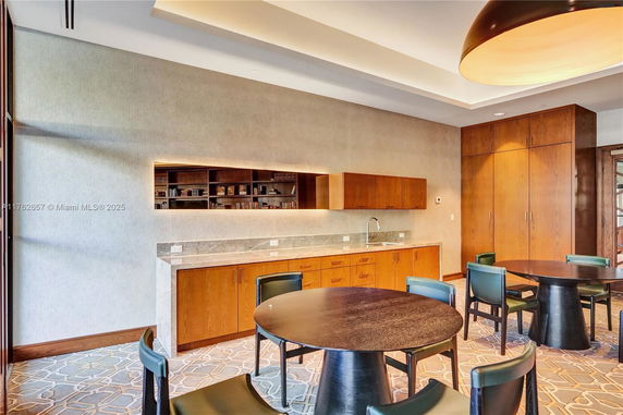 Room with round tables, chairs, and a built-in wooden counter with a sink.