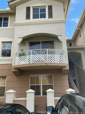 Front view of a multi-story building with a small balcony and white railing.