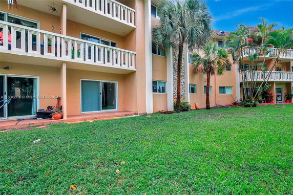 Front view of a multi-story residential building with balconies and sliding glass doors.