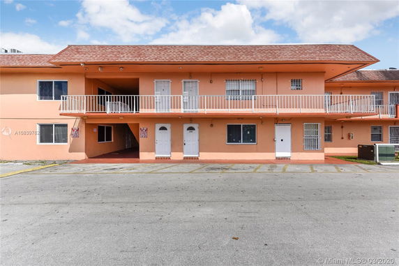 Front view of a two-story apartment building with a walkway and parking area.