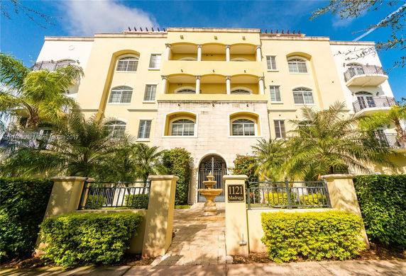 Front view of a multi-story building with balconies and gated entrance.