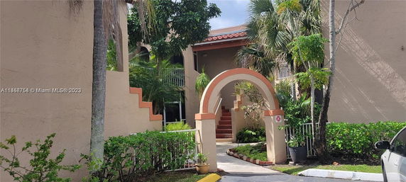 Front view of a building with an arched entrance and stairs leading up.