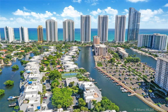 Panoramic view of tall condominium buildings near the coastline with water channels and residential areas in the foreground.