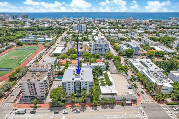 Aerial view of a coastal town with mid-rise buildings and a sports field.