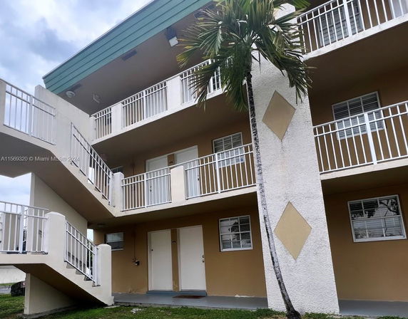 Front view of a multi-story apartment building with exterior staircases and balconies.