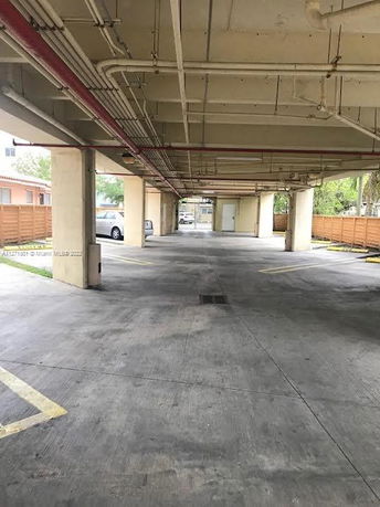 Covered parking area with multiple parking spaces and visible pipes on the ceiling.