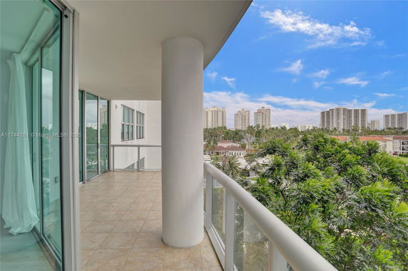View from a building balcony showing nearby high-rise buildings and greenery.