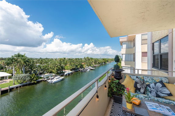 View from a balcony overlooking a waterway with boats and lush greenery.