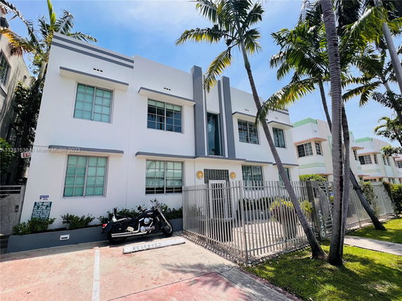 Front view of a multi-story building with large windows and a gated entrance.