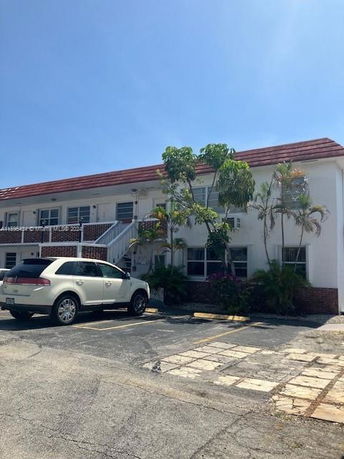 Front view of a two-story building with a red roof and external staircase.