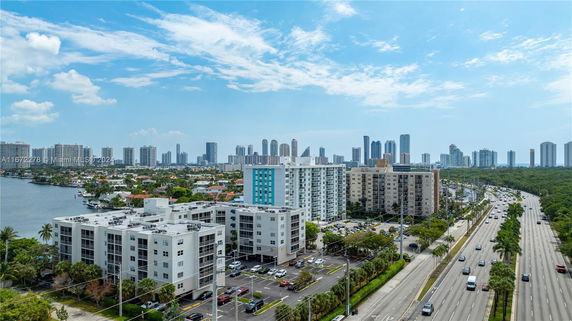 Panoramic view of a cityscape featuring multiple buildings and a wide road with traffic.