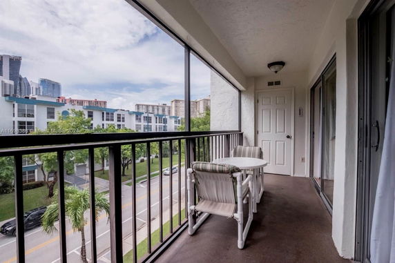 Balcony with outdoor seating overlooking surrounding buildings and street.