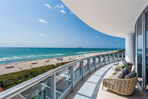 Wide-angle view from a curved balcony overlooking the ocean and beach.