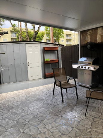 Covered outdoor patio area with chairs and a grill.