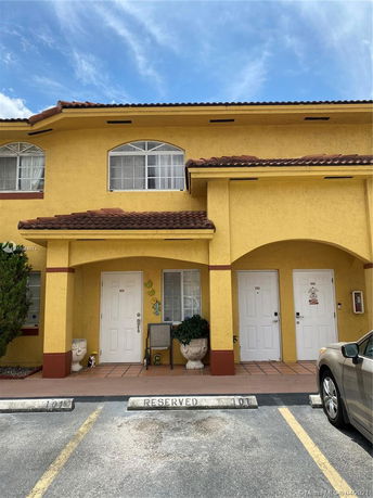 Front view of a two-story building with yellow exterior and arched windows.