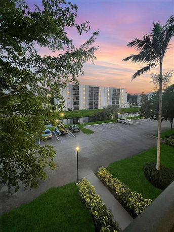 View of surrounding buildings and parking area during sunset, with trees and a path visible.