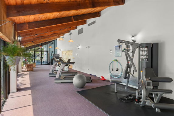 Indoor gym area with exercise equipment and wooden ceiling.