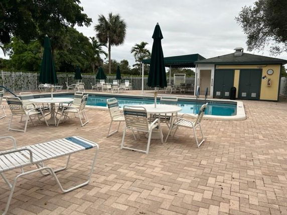 Outdoor swimming pool area with chairs, tables, and umbrellas.