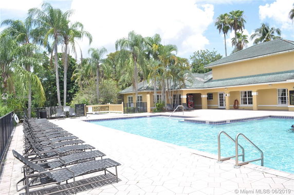 Outdoor swimming pool area with lounge chairs and a building adjacent.