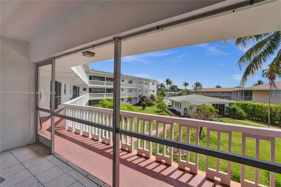 View from a screened balcony overlooking residential buildings and gardens.