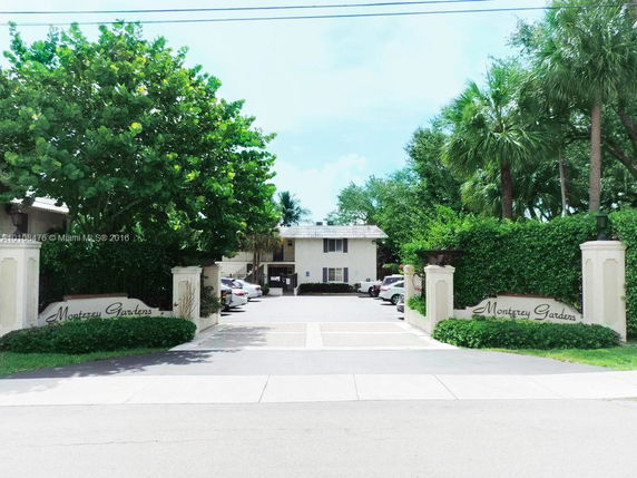 Front view of a residential building with a gated entrance and greenery.