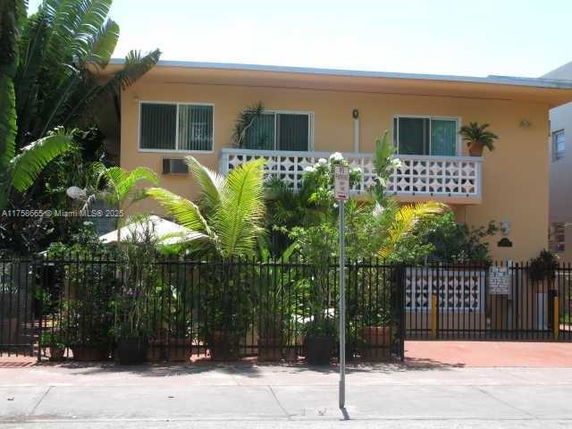 Front view of a two-story house with a fenced yard and balcony.