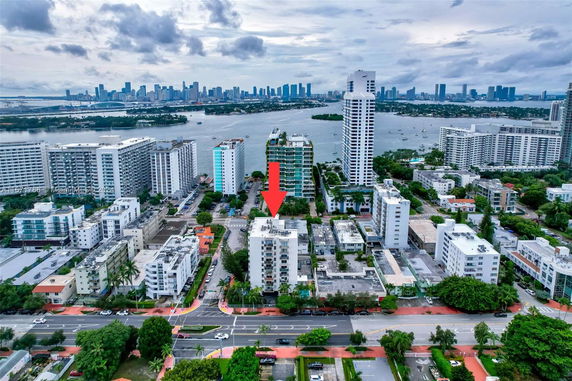 Aerial view of a cityscape with multiple mid-rise buildings and a water body in the background.