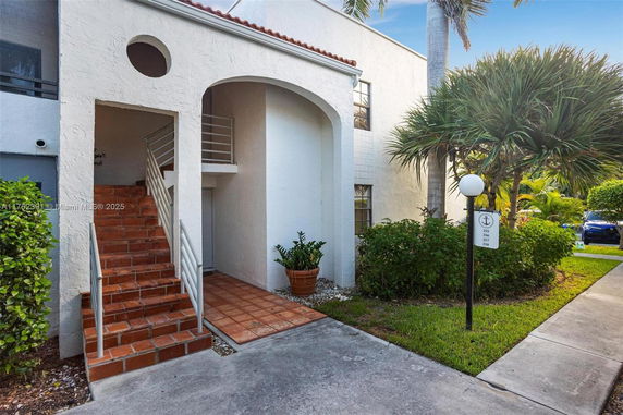 Front view of a white building entrance with stairs and an arched design.