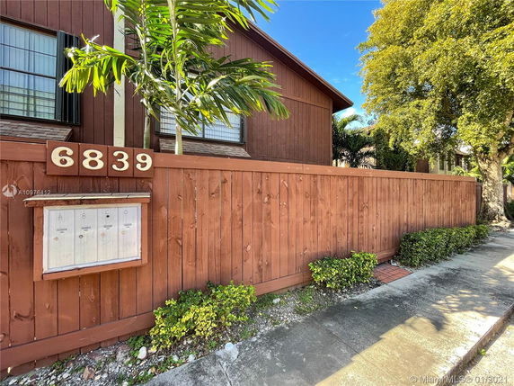 Front view of a house with a wooden fence and mailbox area.