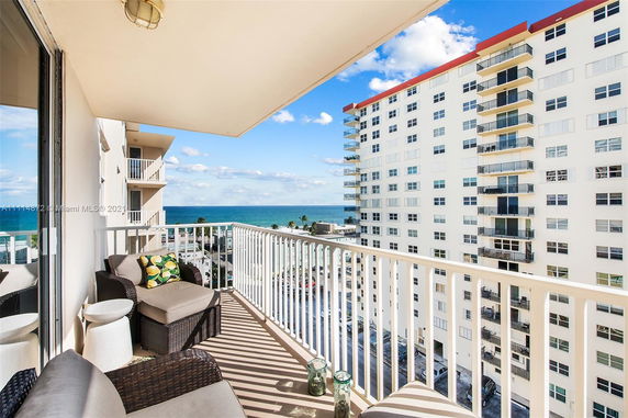 Balcony view from a high-rise building overlooking another apartment building and the ocean.