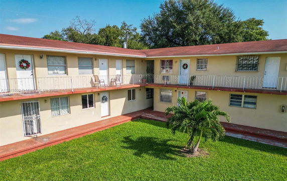 Front view of a two-story residential building with balconies and a central courtyard.