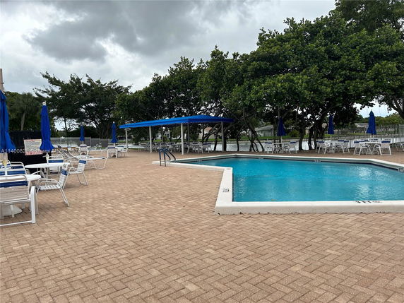 Outdoor swimming pool area with lounge chairs and umbrellas.
