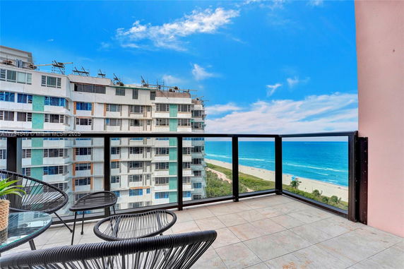 Balcony view showing beachfront and nearby building.