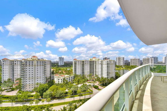 Panoramic view from a balcony overlooking high-rise buildings and lush greenery.