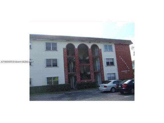 Front view of a three-story apartment building with brick archway design.