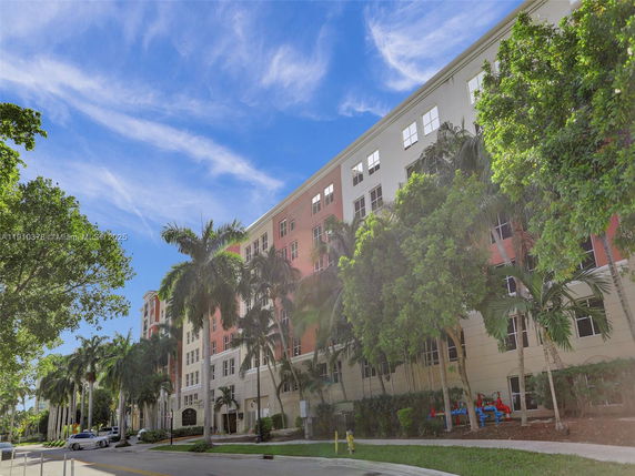 Front view of a multi-story residential building with palm trees.