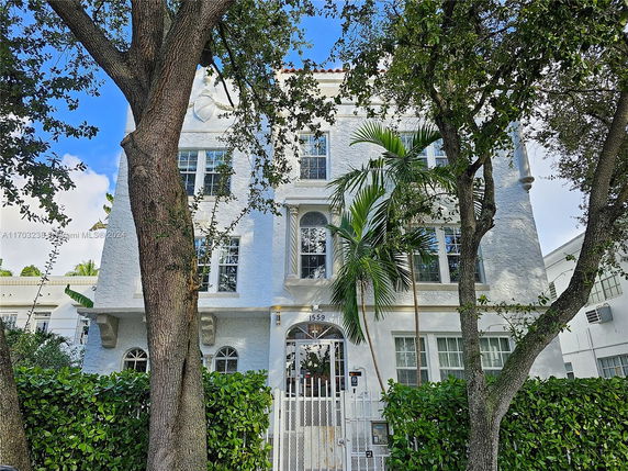Front view of a multi-story building with white exterior and arched windows.