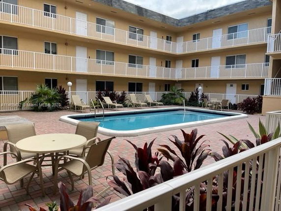 Apartment courtyard with swimming pool and surrounding patio furniture.