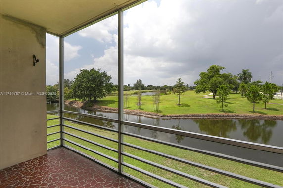 View from a balcony overlooking a grassy landscape with a pond and trees.