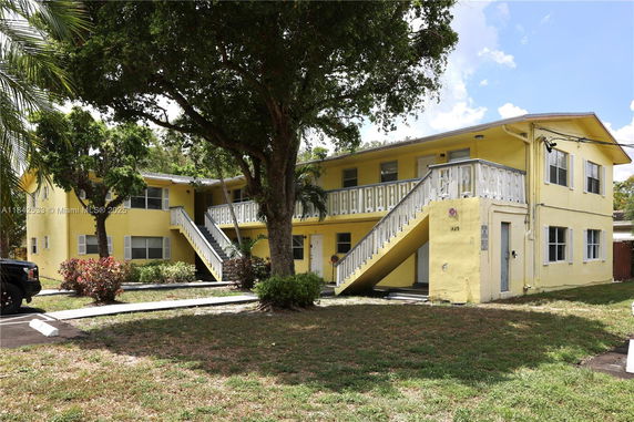 Front view of a two-story yellow apartment building with exterior staircases.