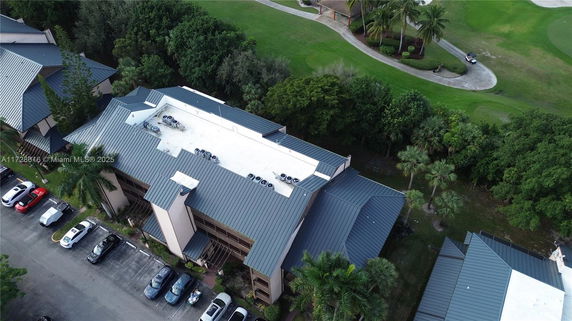 Aerial view of a building with a metal roof and air conditioning units on the rooftop.