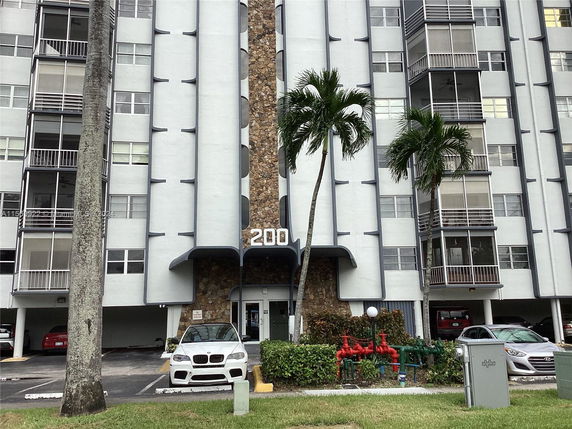 Front view of a multi-story apartment building with balconies and a distinctive stone column design.