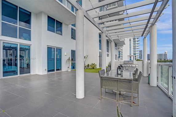 Balcony view of a modern building with glass railings and patio furniture.
