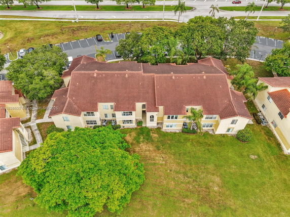 Aerial view of a apartment building with a red-tiled roof and beige walls.