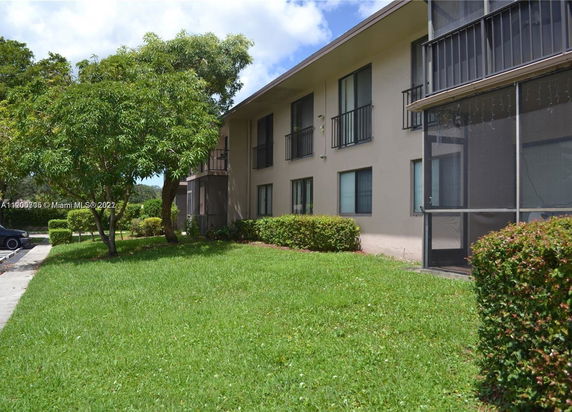 Side view of a two-story apartment building with balconies and screened porches.