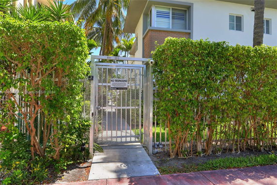 Front view of a building with a gated entrance and surrounding greenery.