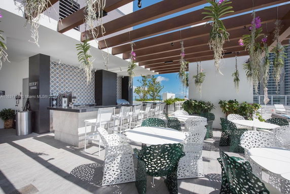 Rooftop lounge area with tables, chairs, and decorative hanging plants.