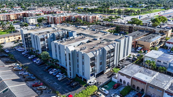 Aerial view of a multi-story residential building surrounded by other buildings and parking areas.